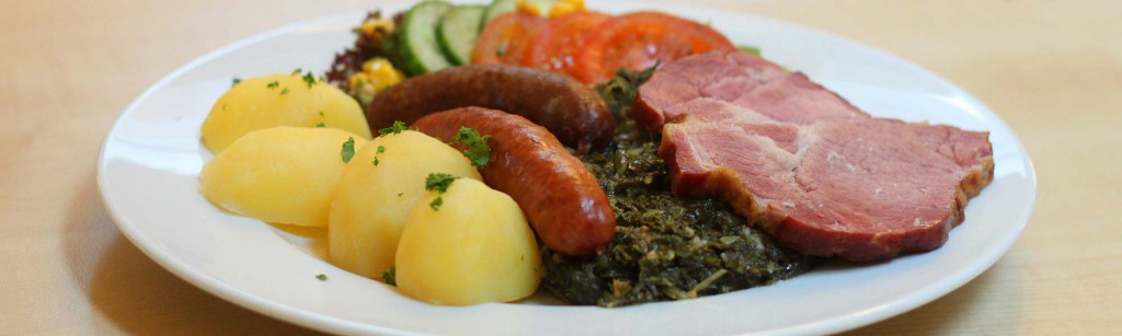 Oldenburger Grünkohl mit Kasseler, Pinkel, Kochwurst und Kartoffeln auf einem Teller