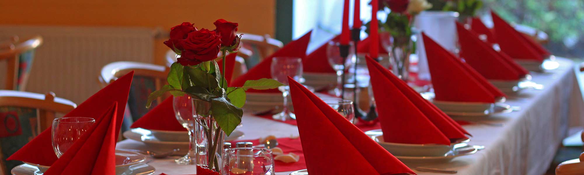 eingedeckter Tisch mit roten Rosen und Servietten