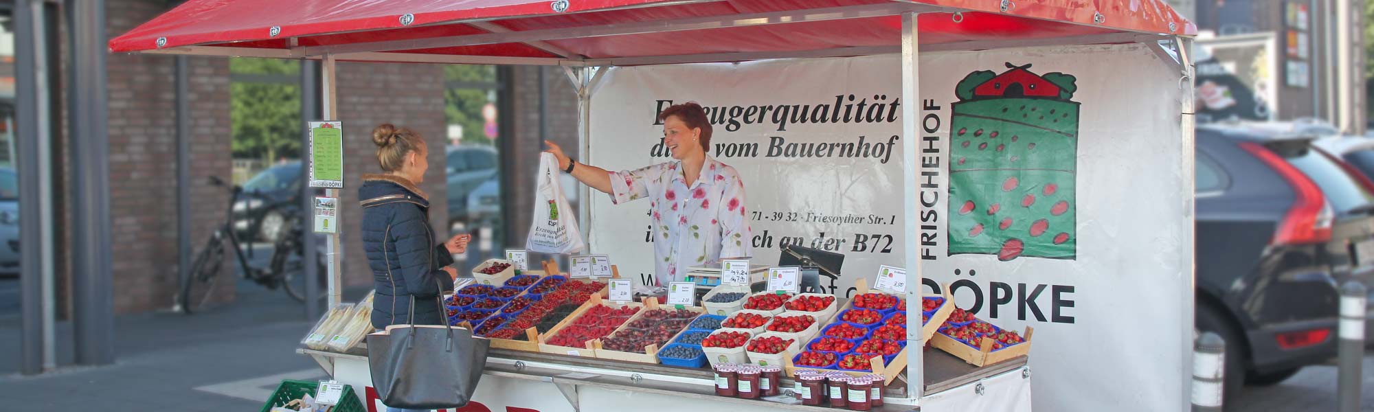 Verkäuferin mit Kundin am Erdbeerverkaufsstand